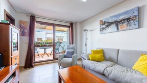 Una sala de estar moderna con un sofá, un sillón, una mesa de centro de madera y un cuadro en la pared.