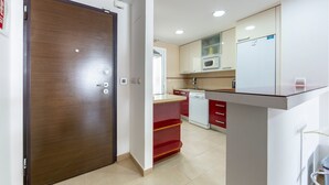 Una cocina con microondas, refrigerador y cajones rojos.