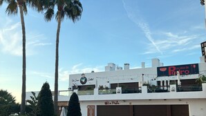 Una terraza en la azotea con palmeras, un restaurante llamado 'La casa de Pedro' y un letrero que dice 'La Pailla'.