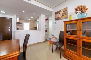 A modern kitchen with a dining area, wooden cabinets, and a decorative vase on the wall.