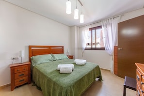 A bedroom with a bed, bedside tables, a wardrobe, and a window with curtains.