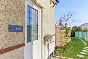 A building labeled 'LOFT STUDIO' with a white door, a window, and a small tree in the yard. - Stylish Harrogate Apartment (North Yorkshire)