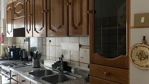 Una cocina con gabinetes de madera, encimeras de granito y electrodomésticos de acero inoxidable, además de un ventanal grande.