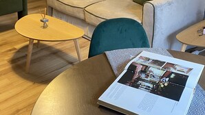 Una sala de estar con un sofá, una mesita redonda, un sillón verde y una estantería.