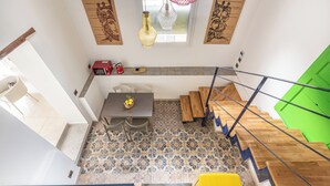 Un comedor con mesa y sillas, una escalera de madera y una puerta verde.
