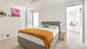 Un dormitorio moderno con una cama, una lámpara de noche y un cuadro en la pared.