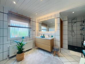 Un bagno moderno con uno specchio grande, un lavandino, una doccia e un termosifone.