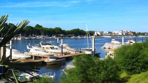 Un puerto deportivo con barcos amarrados, cielo despejado y edificios al fondo.