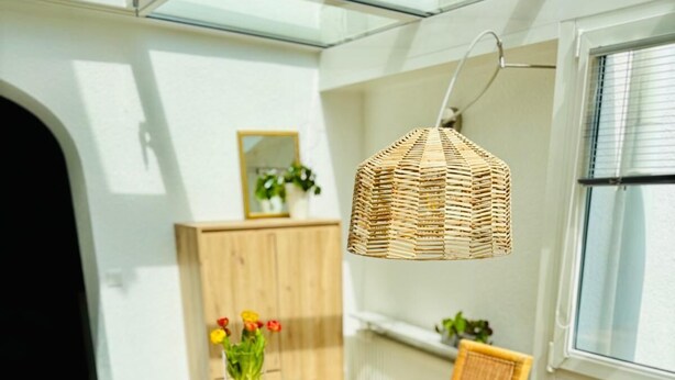 Comedor con una mesa de madera dispuesta para cuatro personas, rodeado de sillas de mimbre.