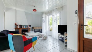 Una sala de estar con sofá, una butaca colorida, televisor, chimenea y estantería.