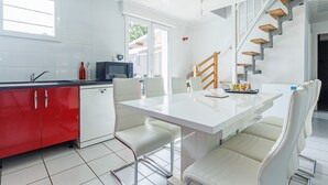 Una cocina moderna con armarios blancos, una mesa de comedor con sillas, un microondas y una escalera.