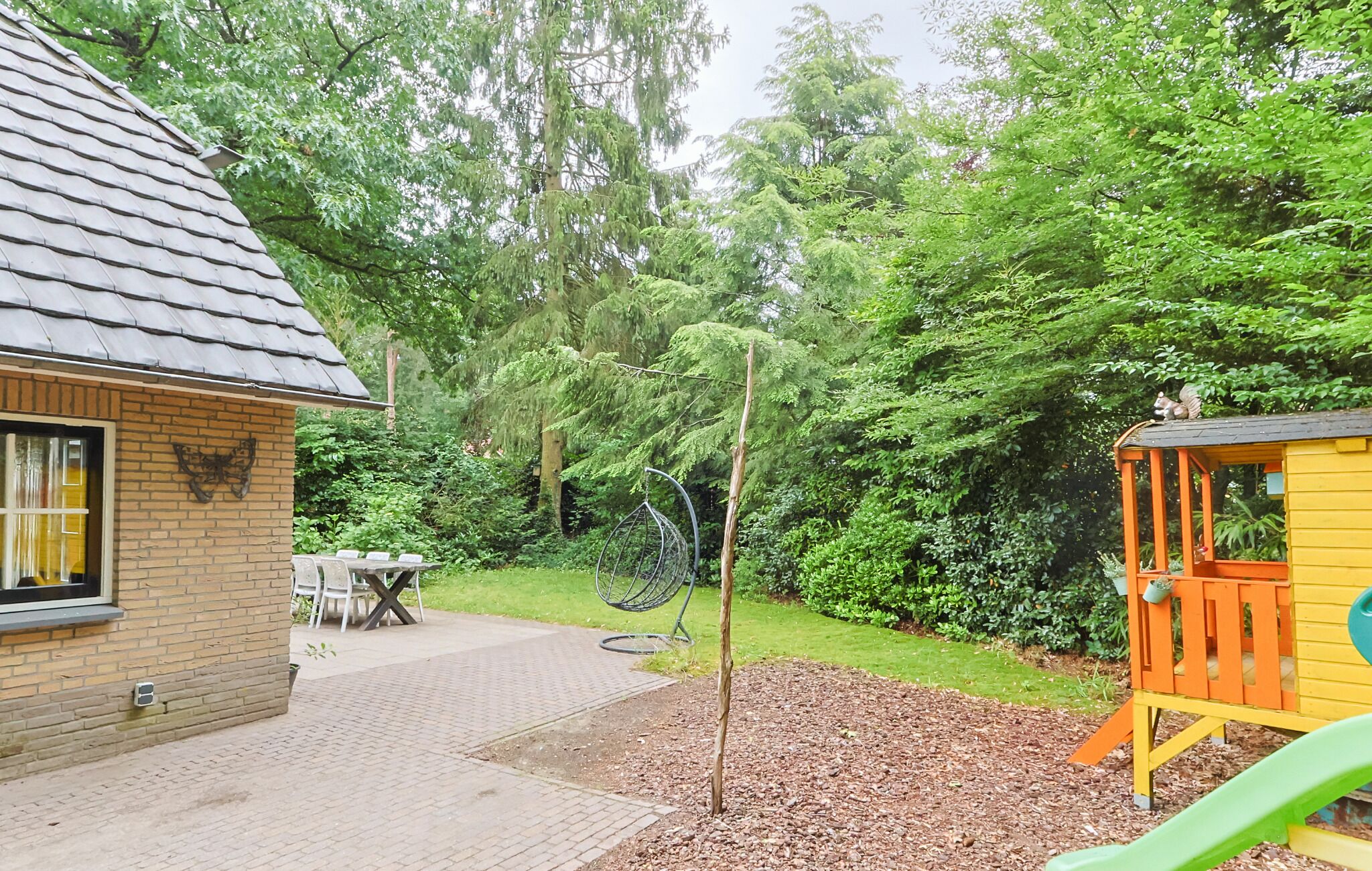 A patio with a table and chairs, a swing set, and a play structure.