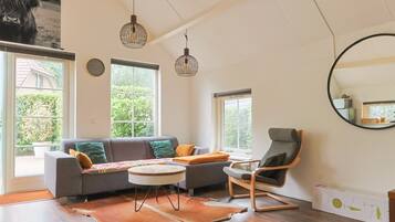 A living room with a sofa, a chair, a round table, and a large mirror.