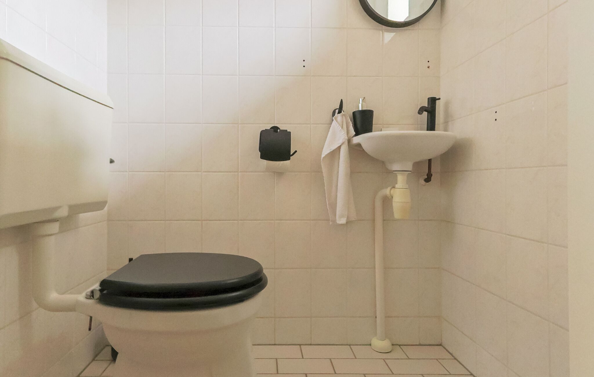 A bathroom with a toilet, sink, and towel hanging on the wall.