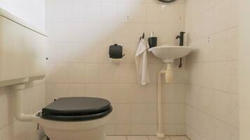 A bathroom with a toilet, sink, and towel hanging on the wall.