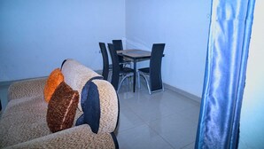 Una habitación con sofá, una mesa de comedor con sillas y una cortina.