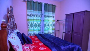 Un dormitorio con cama, armario y ventana con cortinas.