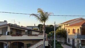 A residential area with a stone staircase leading to a gated entrance, a palm tree, and houses with tiled roofs. - Villa oleanders sea of sicily (Agnone)