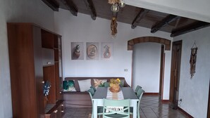A dining area with a table and chairs, a hanging light fixture, and a wall with framed pictures. - Villa oleanders sea of sicily (Agnone)