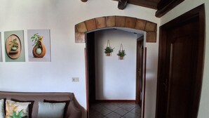 A hallway with a tiled floor, a wooden door, and a brown couch with cushions. - Villa oleanders sea of sicily (Agnone)