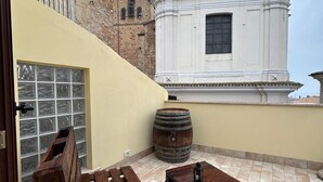 A rooftop terrace with wooden furniture, a barrel, and a view of a white church with a bell tower. - Suite room with private en suite bathroom and terrace (Spoltore)