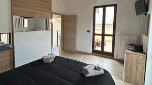 A bedroom with a large bed, wooden ceiling beams, a television, and a sliding glass door leading to a balcony. - Suite room with private en suite bathroom and terrace (Spoltore)