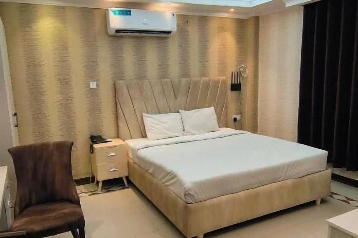 Ein modernes Schlafzimmer mit einem großen Bett, einer Klimaanlage, einem Nachttisch und einem Sessel.