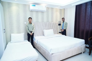 A hotel room with two beds, a large window, and a wall-mounted air conditioner. - Sea Shell Palace (Dhaka)