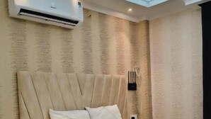 A bedroom with a bed, bedside tables, an air conditioning unit, and a nightstand. - Sea Shell Palace (Dhaka)