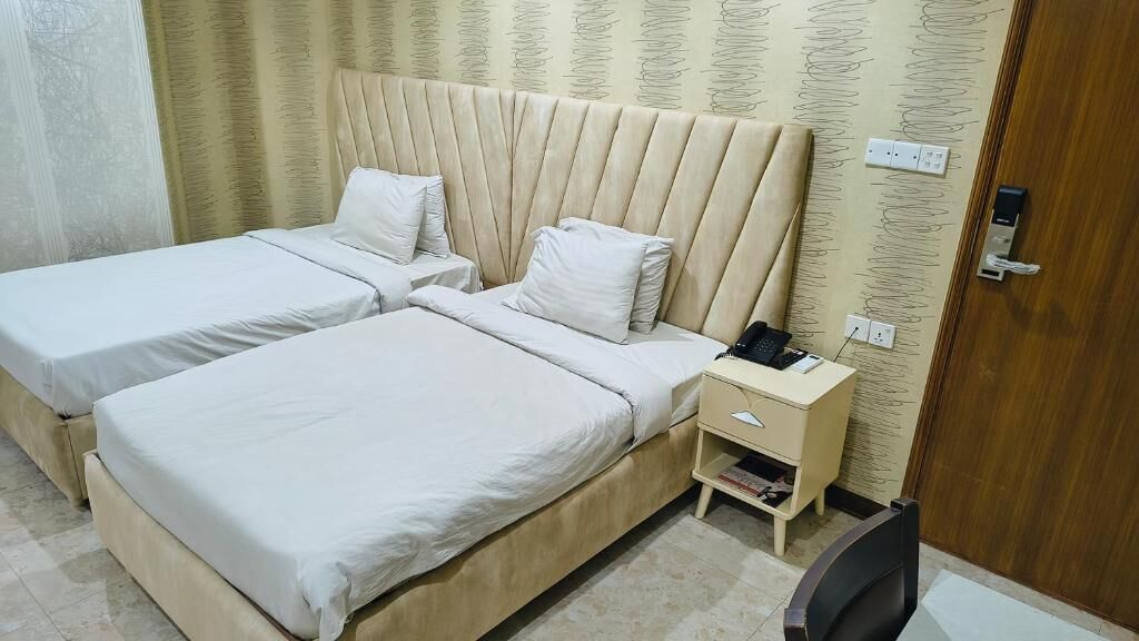 Habitación de hotel con dos camas, una mesita de noche con teléfono y una silla.
