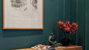 A wooden bench with a framed artwork and a vase of flowers against teal walls. - Boutique Interior Designed One Bed Apartment (North Yorkshire)