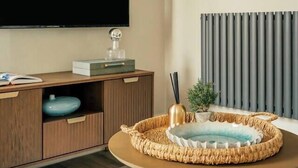A modern living room with a flat-screen TV, a wooden cabinet, a round coffee table, and a wall-mounted artwork. - Boutique Interior Designed One Bed Apartment (North Yorkshire)