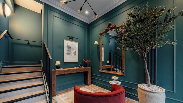 A staircase leading to a landing with a red ottoman and a large potted plant. - Boutique Interior Designed One Bed Apartment (North Yorkshire)