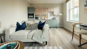 A living room with a sofa, a dining table, and a kitchen area with cabinets and appliances. - Boutique Interior Designed One Bed Apartment (North Yorkshire)