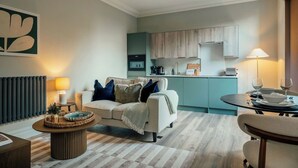 A modern living room with a sofa, coffee table, and dining area. - Boutique Interior Designed One Bed Apartment (North Yorkshire)