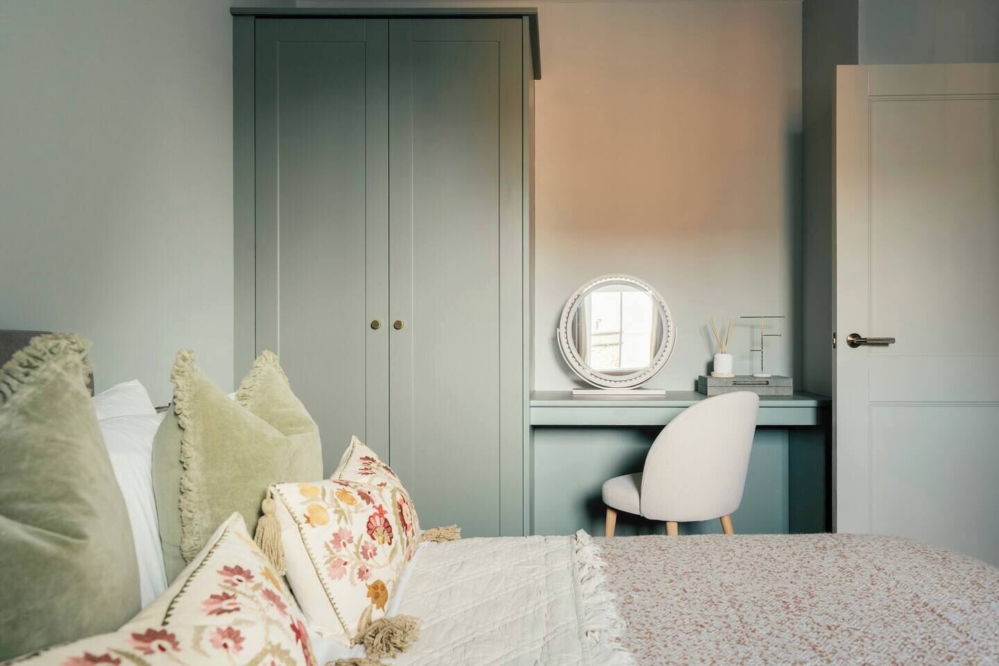 Un dormitorio con cama, escritorio con espejo y armario.