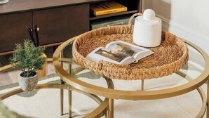 Un soggiorno moderno con un tavolino da caffè rotondo in vetro, un mobile contenitore in legno scuro, un televisore a schermo piatto e una piccola pianta in vaso.
