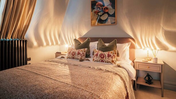 Una camera da letto con un letto grande, un comodino, una lampada e un quadro appeso al muro.