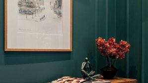 A wooden bench with a framed picture above it, a small statue, and a vase with flowers. - Beautiful One Bedroom Apartment | Town Centre (North Yorkshire)