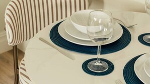A round dining table with a white marble top, a striped upholstered chair, and blue placemats. - Beautiful One Bedroom Apartment | Town Centre (North Yorkshire)