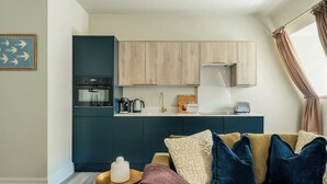 A modern kitchen with dark cabinets, a built-in oven, and a coffee maker. - Beautiful One Bedroom Apartment | Town Centre (North Yorkshire)