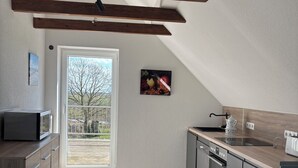 A modern kitchen with a wooden ceiling, a large window, and a kitchen island. - Huus Diekblick Ditzum (Bunde)