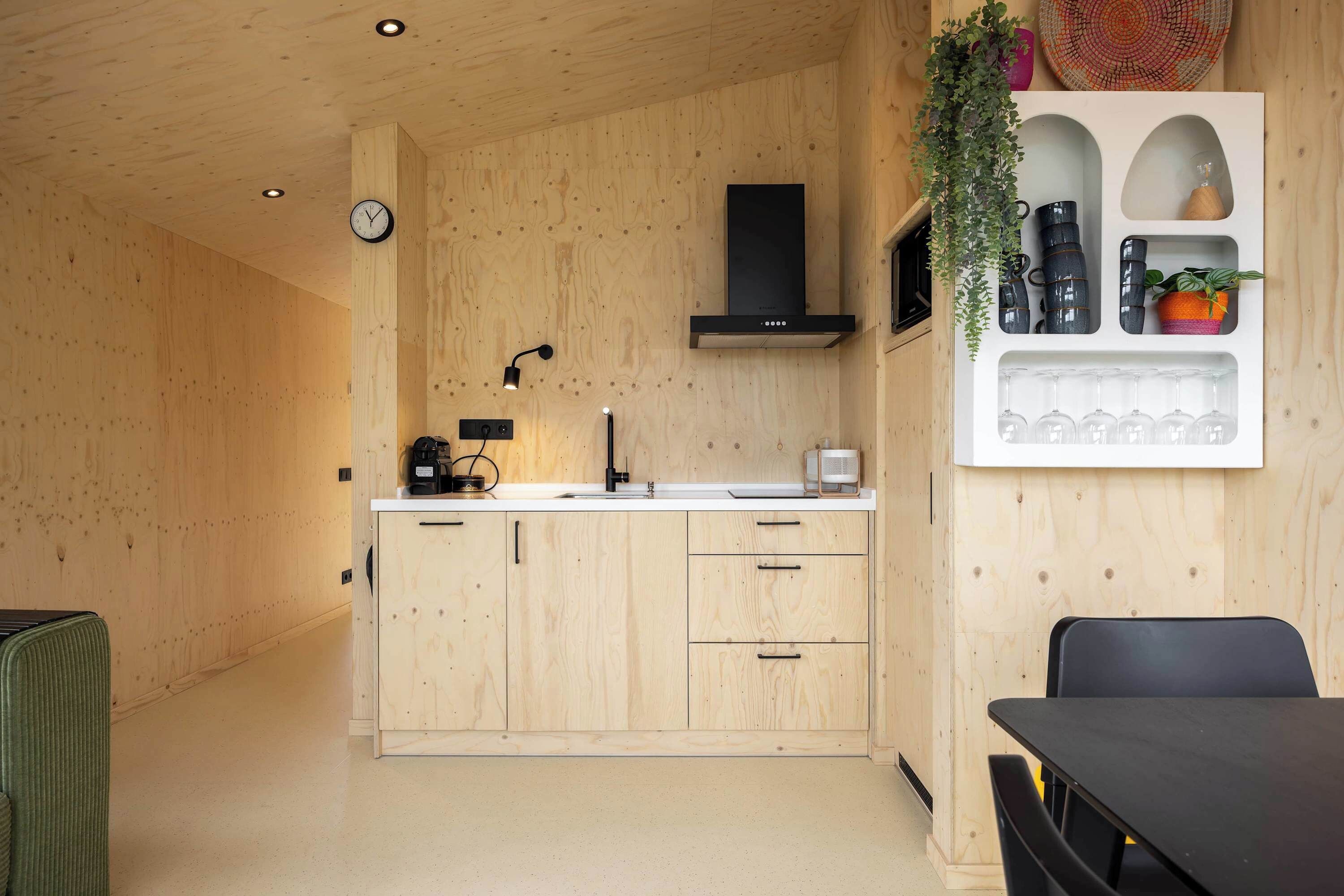 A wooden interior with a kitchen area, including a sink, cabinets, and a microwave.