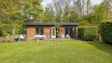Een modern huis met een terras, twee stoelen en een tafel.