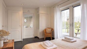A bedroom with a bed, a chair, a dresser, and a window with curtains.