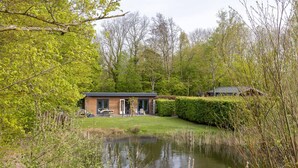 Ein Haus mit Teich, umgeben von Bäumen und einer Hecke.