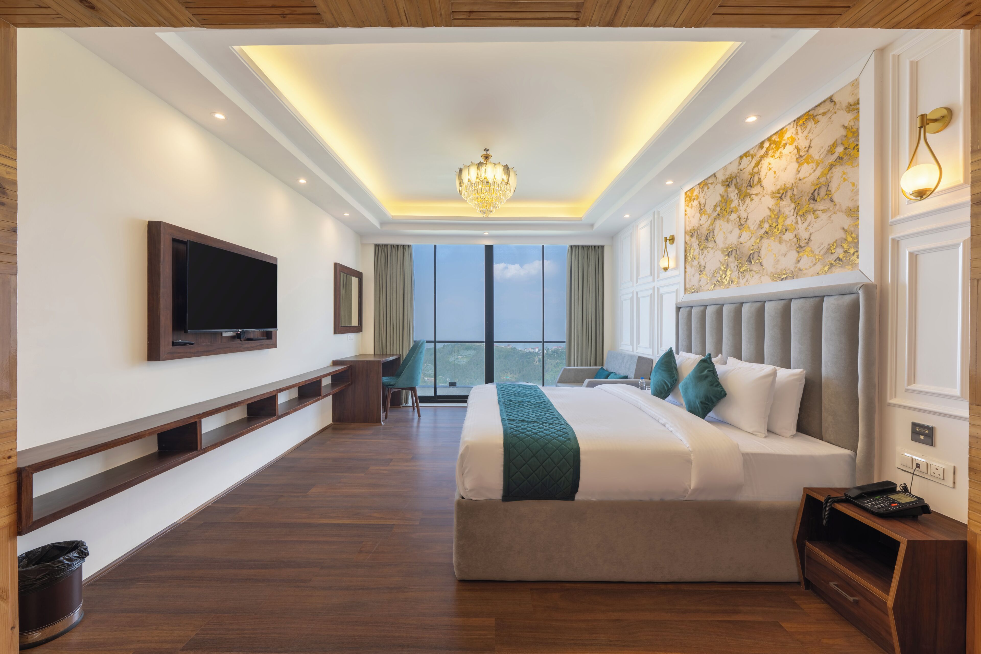 A hotel room with a large bed, a television mounted on the wall, a desk, and a view of the city.