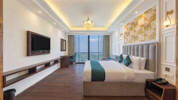 A hotel room with a large bed, a television mounted on the wall, a desk, and a view of the city.