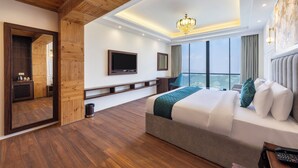 Habitación de hotel con techo de madera, cama grande, televisor, escritorio y vistas al exterior.