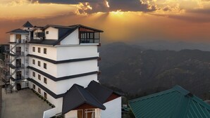 Un edificio de varios pisos con balcón, escape de incendios y vistas a las montañas.